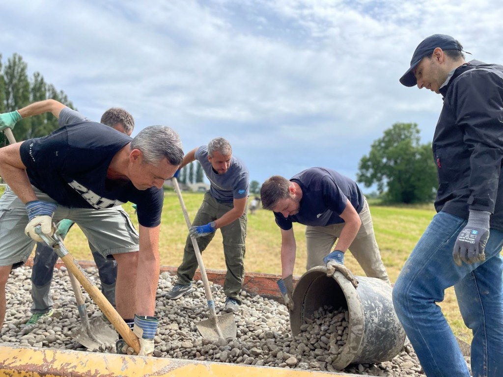 Volunteers work together to move a massive pile of rocks after their tractor broke down.