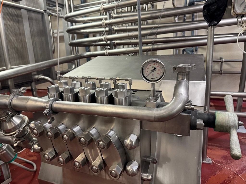 The current cheese production facility is back up and running, and stainless pipes carry the milk and cream from station to station. A Clean in Place system sterilizes the machinery after a batch is made.