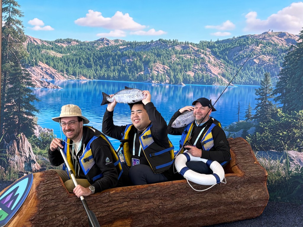 Attendees pose inside a wooden canoe at a photo op.