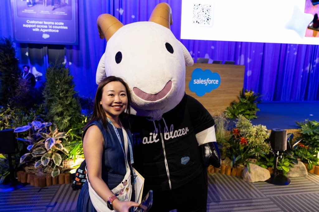 An attendee poses with Cloudy the Goat before a keynote.
