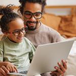 Vader en dochter bekijken laptop