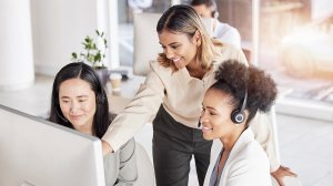 Three professionally dressed women review customer service operations on a computer.