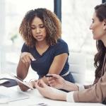 twee vrouwen aan een bureau kijken naar een laptop
