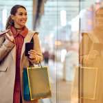 Vrouw met shopping bags en mobiele telefoon: voorspellingen feestdagen 2023