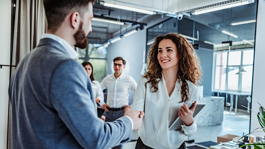 Man and woman are shaking hands in office.