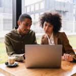 Two people discussing findings of AI-powered CRM research in front of computer.