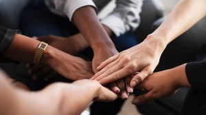 Afbeelding van een groep mensen die hun handen op elkaar leggen / model voor gedeelde verantwoordelijkheid