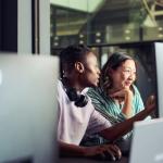 Twee mensen op het werk die naar een computerscherm kijken.